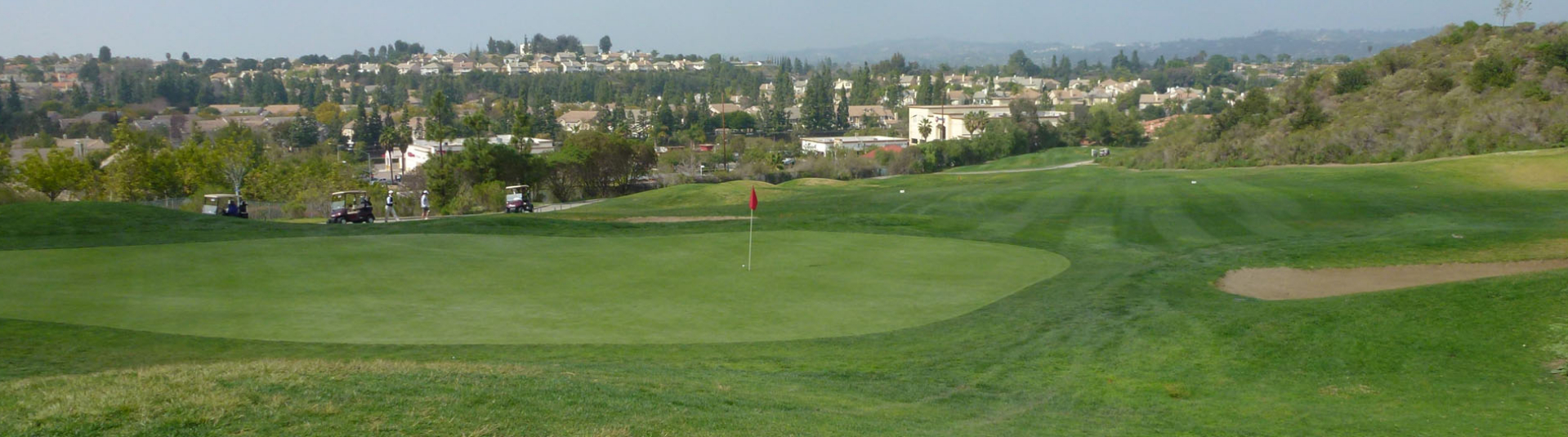 view of golf course green with town in background